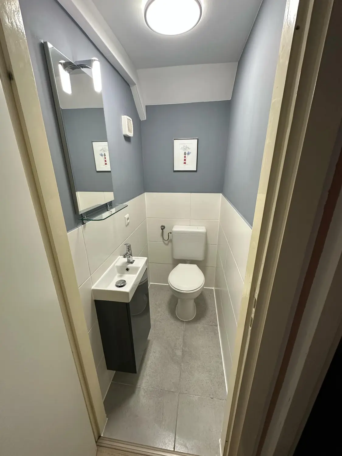 Fertiges Gäste-WC mit blauen Wänden und weißen Fliesen